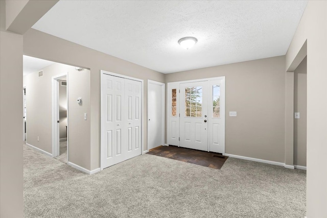 carpeted foyer entrance with a textured ceiling