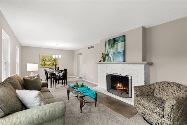 carpeted living room featuring a chandelier and a brick fireplace