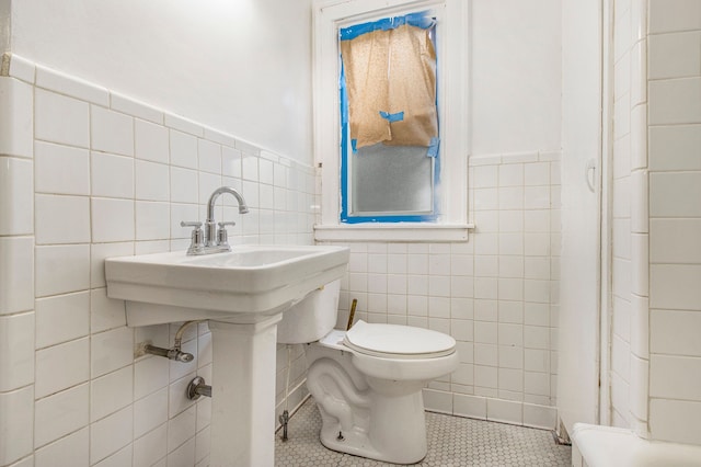 bathroom featuring tile patterned flooring, tile walls, and toilet