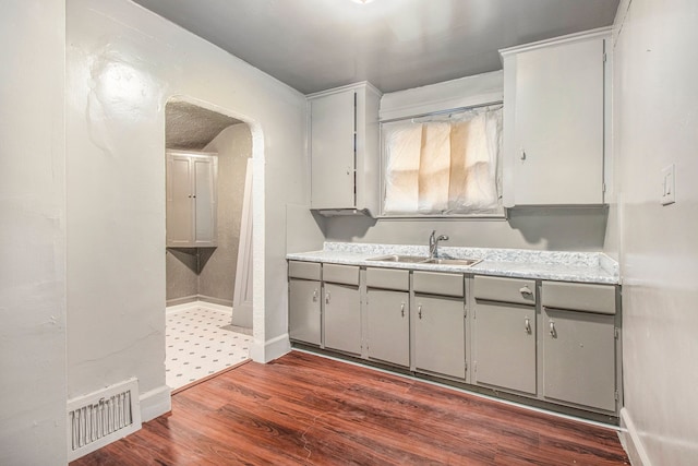 15766 Snowden St, Detroit, MI 48227 - kitchen featuring a sink, gray cabinetry, arched walkways, dark wood finished floors, and light countertops