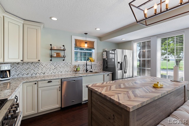 kitchen featuring light stone countertops, appliances with stainless steel finishes, dark hardwood / wood-style flooring, tasteful backsplash, and hanging light fixtures