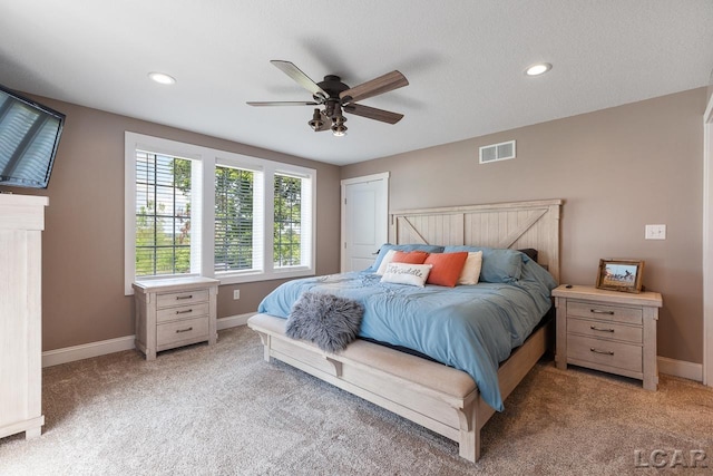 carpeted bedroom featuring ceiling fan and a textured ceiling