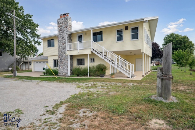 view of front of property featuring covered porch, a garage, and a front lawn