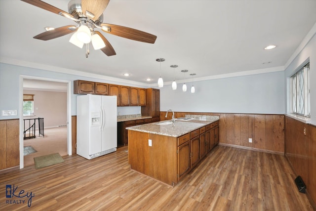 kitchen featuring light stone countertops, ceiling fan, white refrigerator with ice dispenser, wood-type flooring, and pendant lighting