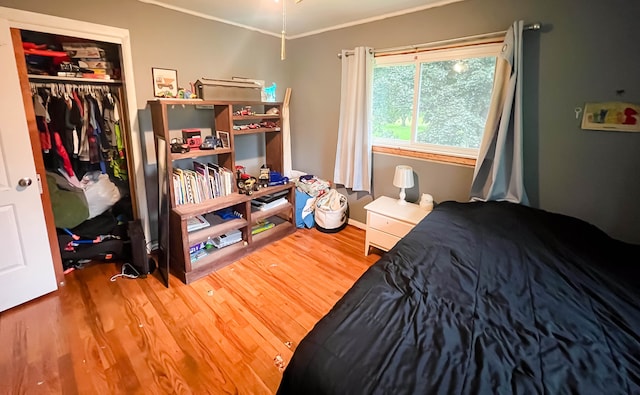 bedroom with hardwood / wood-style flooring, a closet, and crown molding