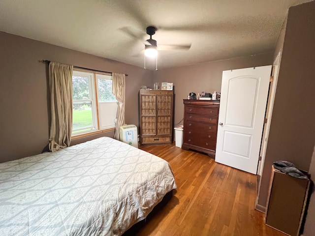 bedroom featuring hardwood / wood-style floors, ceiling fan, and a textured ceiling