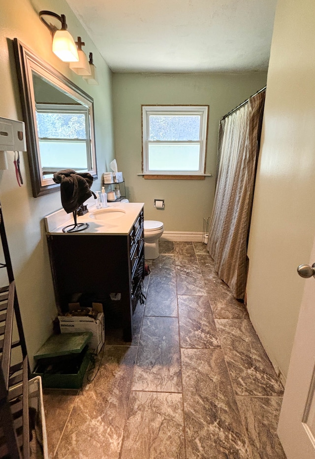 bathroom featuring plenty of natural light, toilet, walk in shower, and vanity