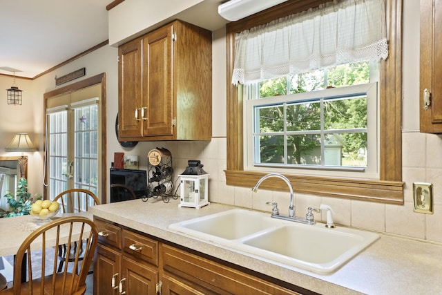 kitchen featuring tasteful backsplash, crown molding, and sink