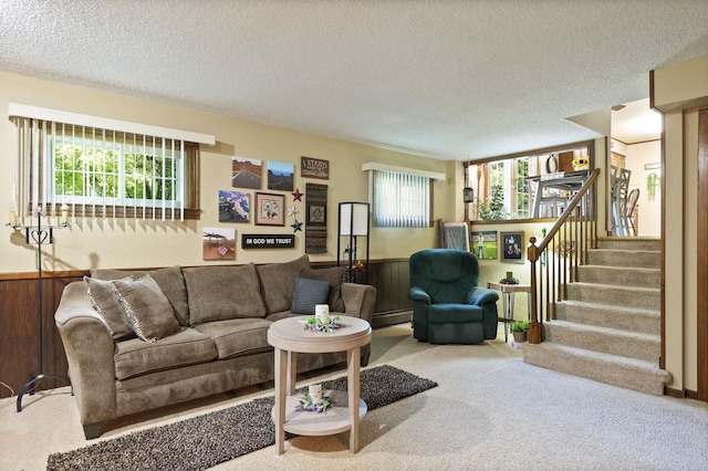 carpeted living room with plenty of natural light, wood walls, and a textured ceiling