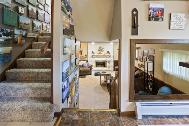 stairs featuring carpet flooring, high vaulted ceiling, and a brick fireplace