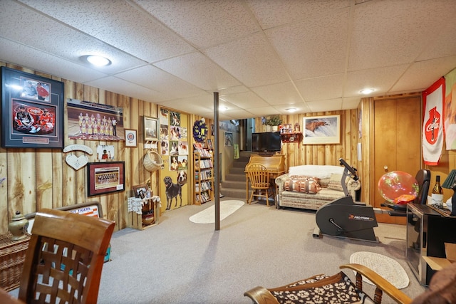 interior space featuring carpet flooring, a paneled ceiling, and wooden walls