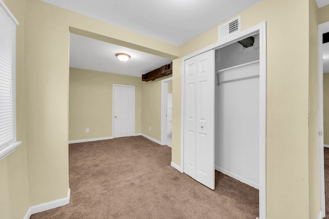 unfurnished bedroom with light colored carpet and a closet