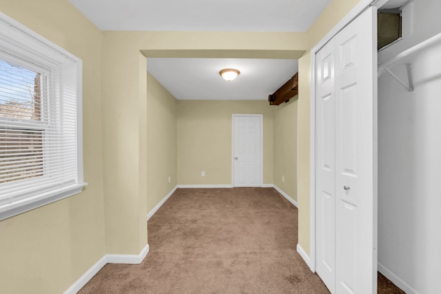 hallway with beam ceiling and light carpet