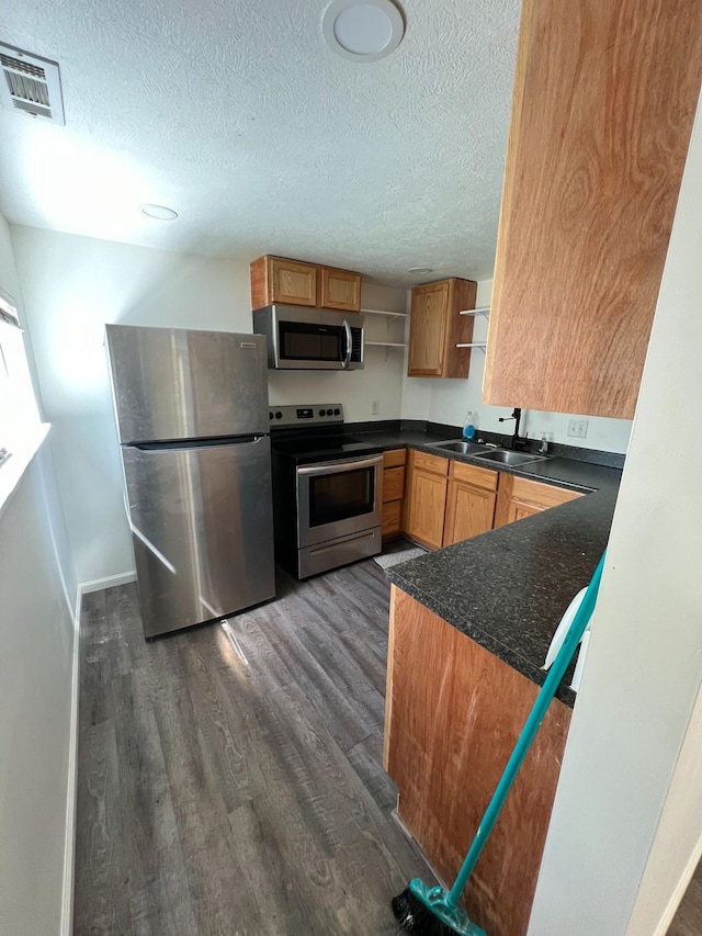 kitchen featuring a textured ceiling, sink, appliances with stainless steel finishes, and dark wood-type flooring