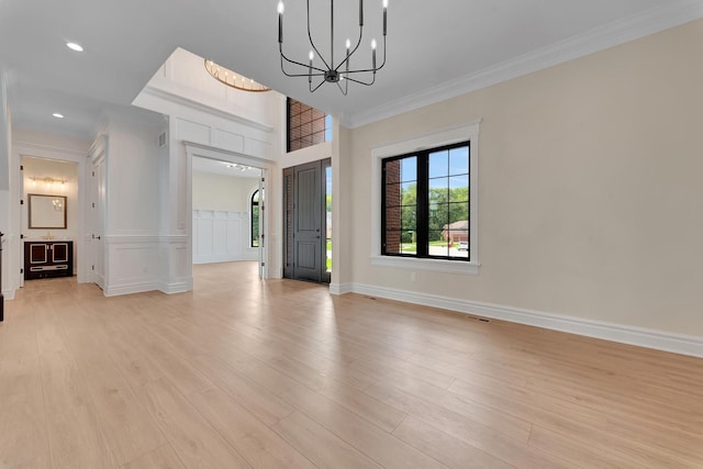 interior space with light wood-type flooring, crown molding, and a chandelier