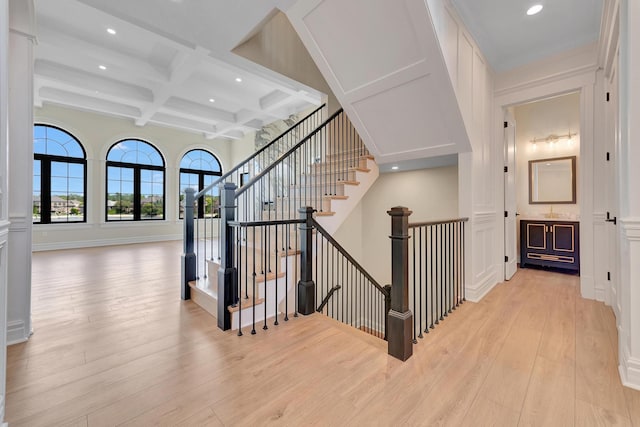 stairway featuring beamed ceiling, wood-type flooring, and coffered ceiling