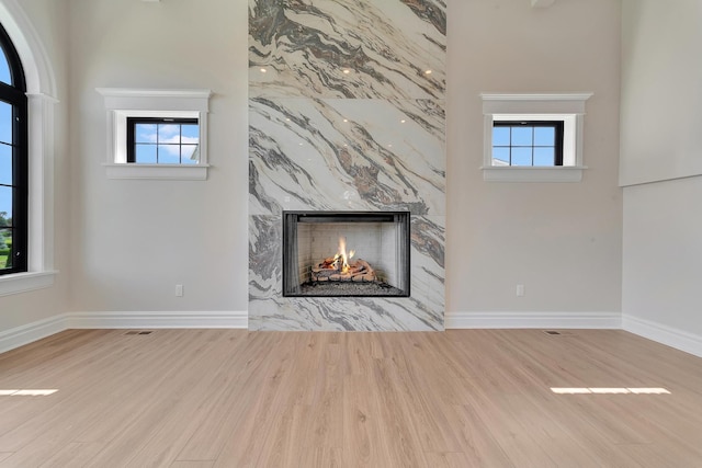 unfurnished living room featuring a wealth of natural light, light hardwood / wood-style flooring, and a high end fireplace