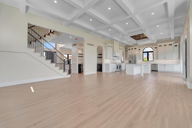 unfurnished living room featuring beam ceiling, coffered ceiling, and light wood-type flooring