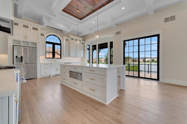 kitchen featuring a center island, stainless steel appliances, tasteful backsplash, pendant lighting, and light hardwood / wood-style floors