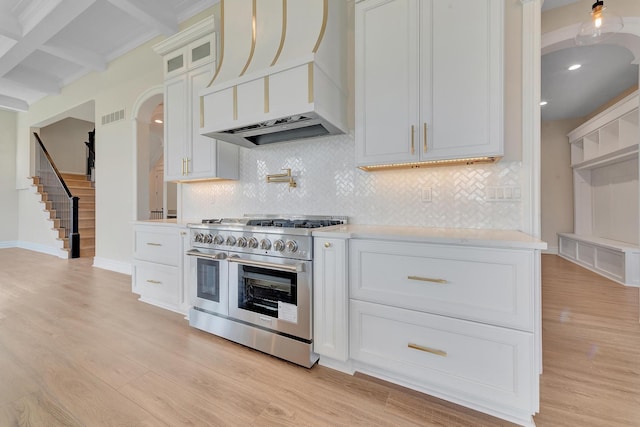 kitchen with white cabinetry, double oven range, light wood-type flooring, and custom range hood