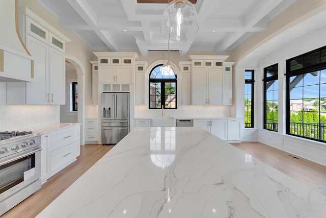 kitchen with light hardwood / wood-style flooring, hanging light fixtures, and appliances with stainless steel finishes