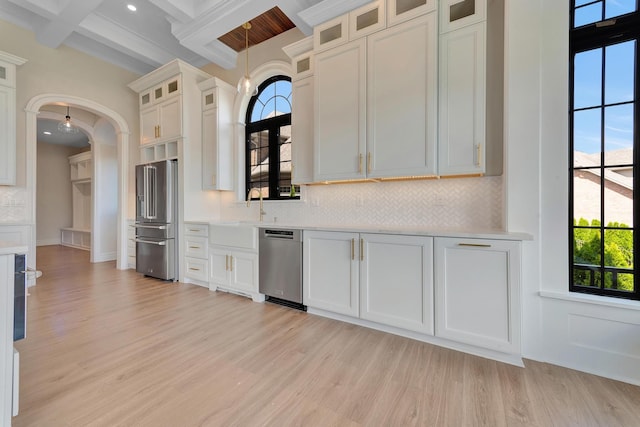 kitchen featuring beam ceiling, a healthy amount of sunlight, light hardwood / wood-style floors, and stainless steel appliances