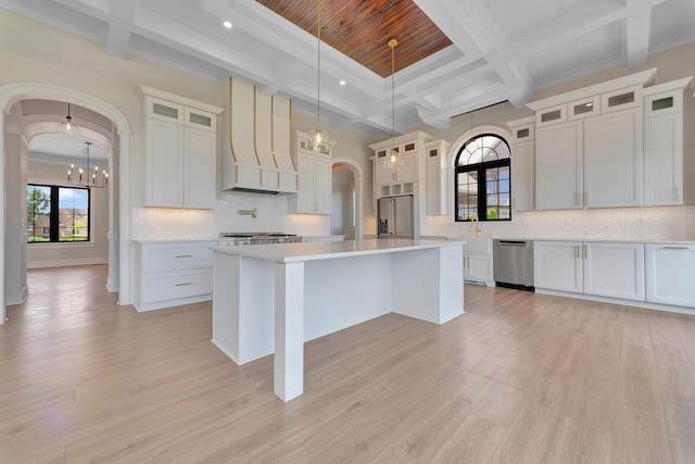 kitchen featuring a center island, light hardwood / wood-style flooring, decorative light fixtures, custom range hood, and stainless steel appliances