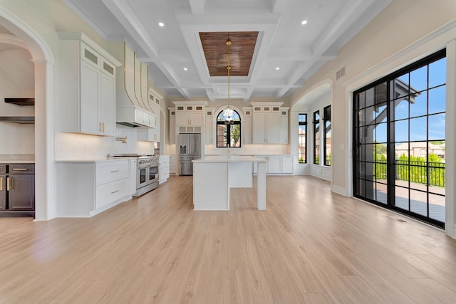 kitchen with a wealth of natural light, pendant lighting, light hardwood / wood-style floors, high quality appliances, and a kitchen island