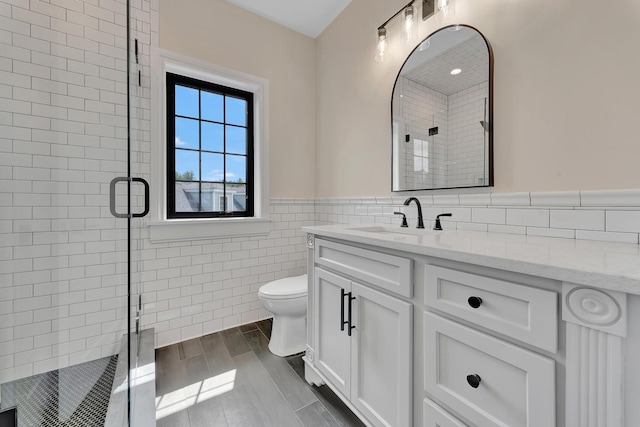 bathroom featuring vanity, hardwood / wood-style flooring, toilet, tile walls, and an enclosed shower