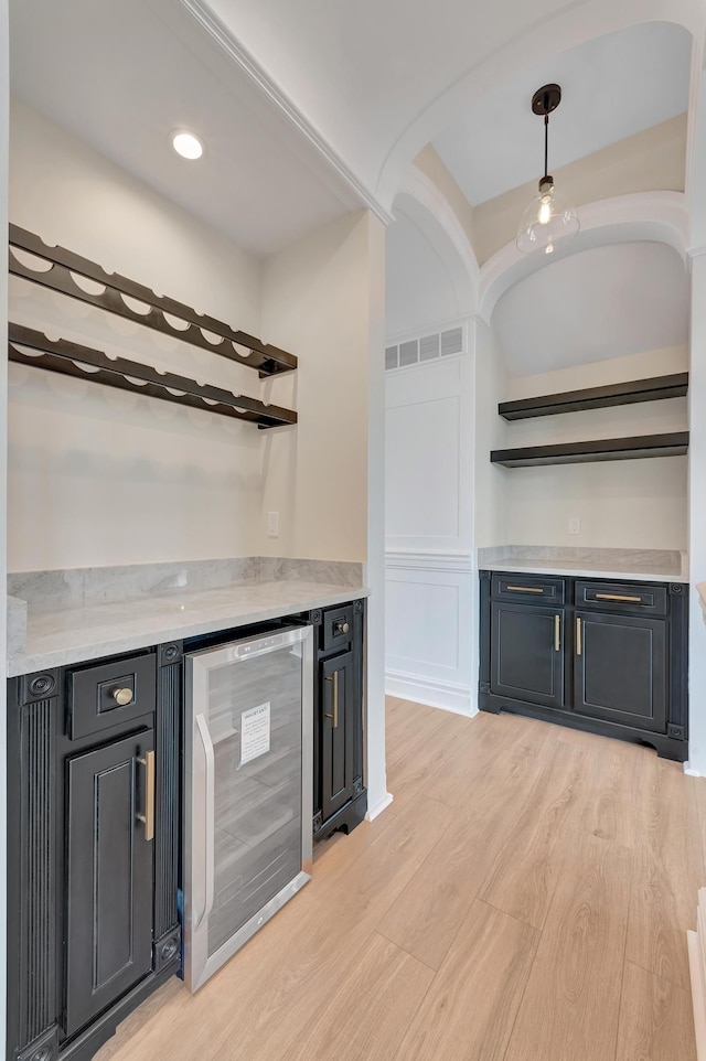 bar with pendant lighting, light wood-type flooring, and beverage cooler