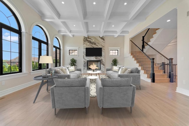 living room with beam ceiling, light wood-type flooring, a fireplace, and coffered ceiling