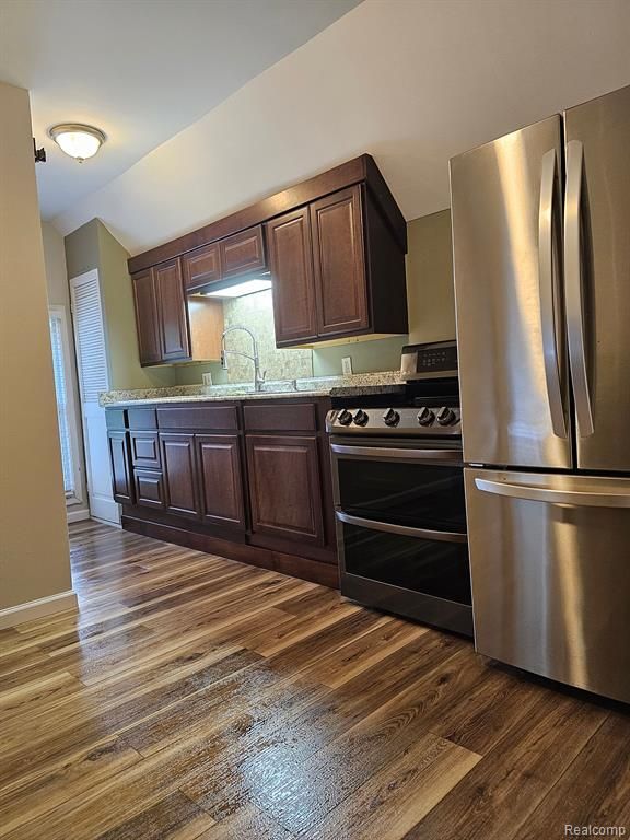 kitchen featuring dark brown cabinets, dark wood-type flooring, and appliances with stainless steel finishes