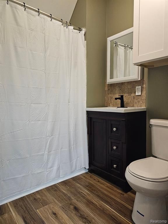 bathroom featuring tasteful backsplash, hardwood / wood-style floors, vanity, and toilet