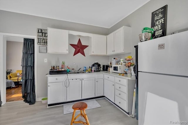 kitchen with white appliances, light hardwood / wood-style floors, white cabinetry, and sink