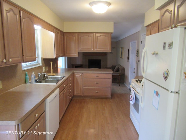 kitchen with kitchen peninsula, a brick fireplace, white appliances, sink, and light hardwood / wood-style flooring