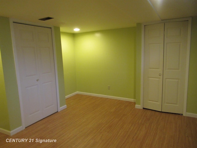 unfurnished bedroom with light hardwood / wood-style floors and two closets