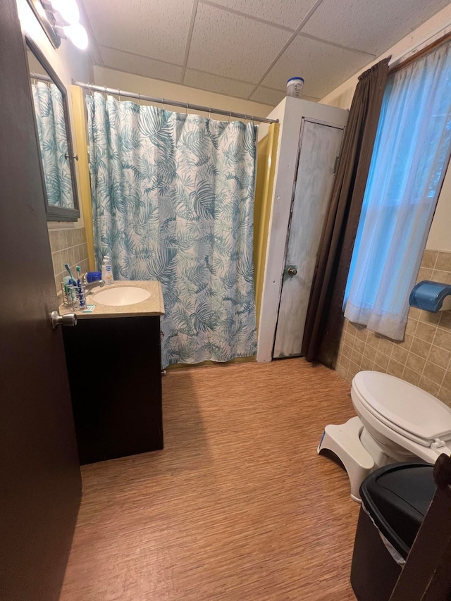 bathroom featuring a drop ceiling, vanity, hardwood / wood-style floors, and tile walls