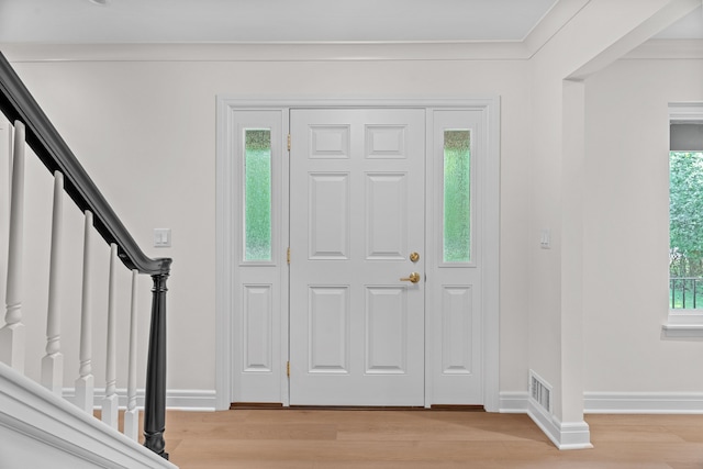 entryway with ornamental molding and light wood-type flooring