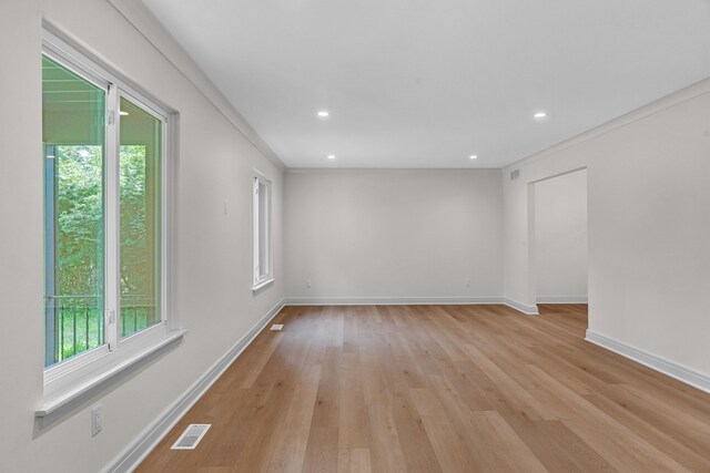 empty room featuring light wood-type flooring and ornamental molding