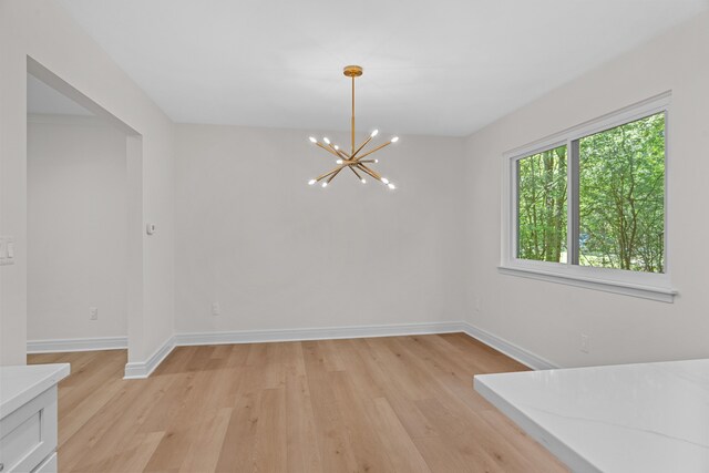 unfurnished dining area featuring light hardwood / wood-style flooring and an inviting chandelier