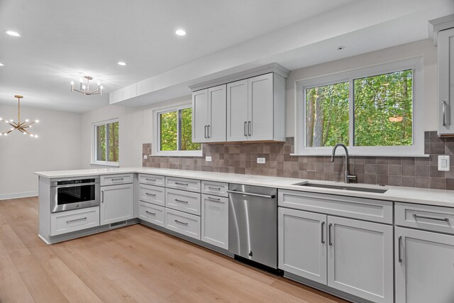 kitchen featuring stainless steel appliances, light hardwood / wood-style flooring, tasteful backsplash, and sink