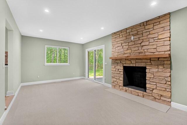 unfurnished living room with a stone fireplace and light carpet