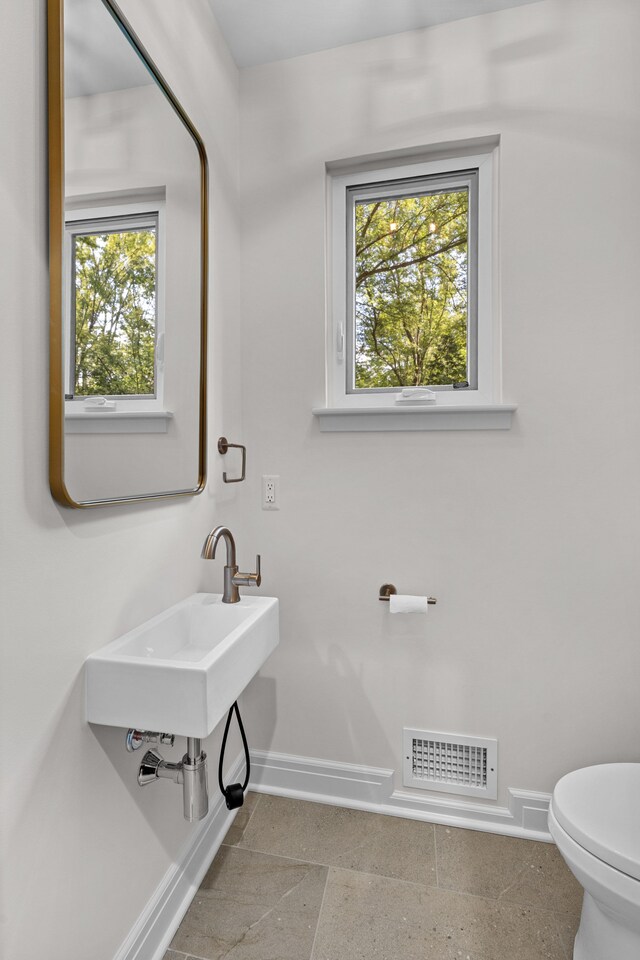 bathroom featuring a healthy amount of sunlight, toilet, and sink