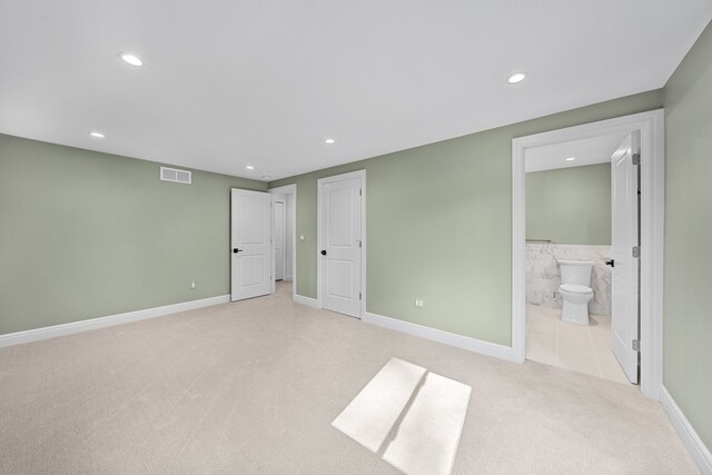 unfurnished bedroom featuring connected bathroom and light colored carpet