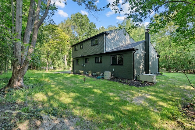 rear view of property featuring cooling unit and a yard