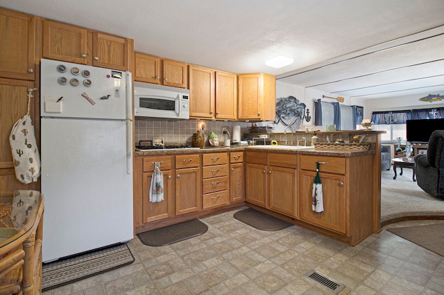 kitchen featuring white appliances, sink, a textured ceiling, tasteful backsplash, and kitchen peninsula