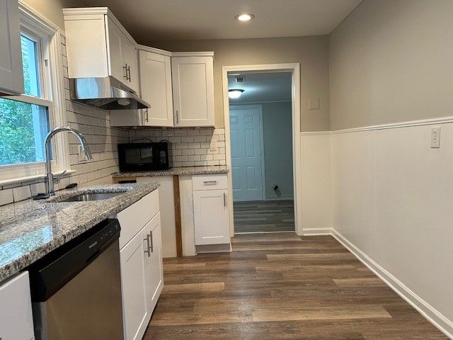 kitchen featuring dark hardwood / wood-style flooring, white cabinetry, sink, and stainless steel dishwasher