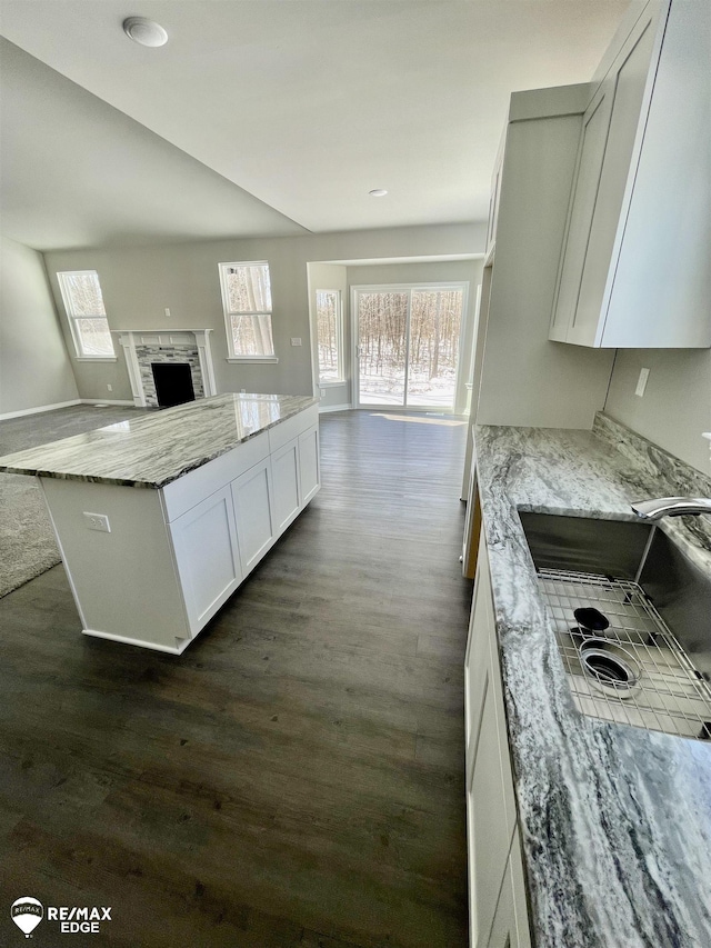 kitchen featuring dark hardwood / wood-style flooring, sink, light stone countertops, and white cabinets