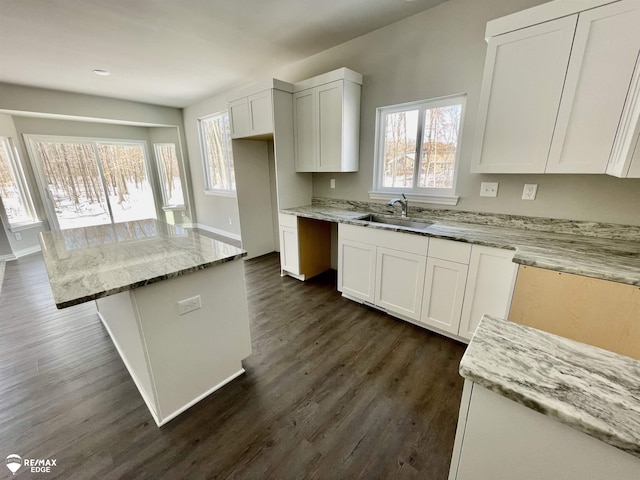 kitchen featuring white cabinetry, a kitchen island, sink, and light stone counters