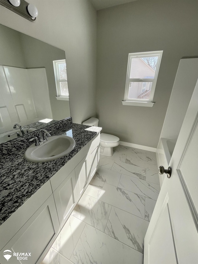 bathroom with vanity, a tub to relax in, and toilet